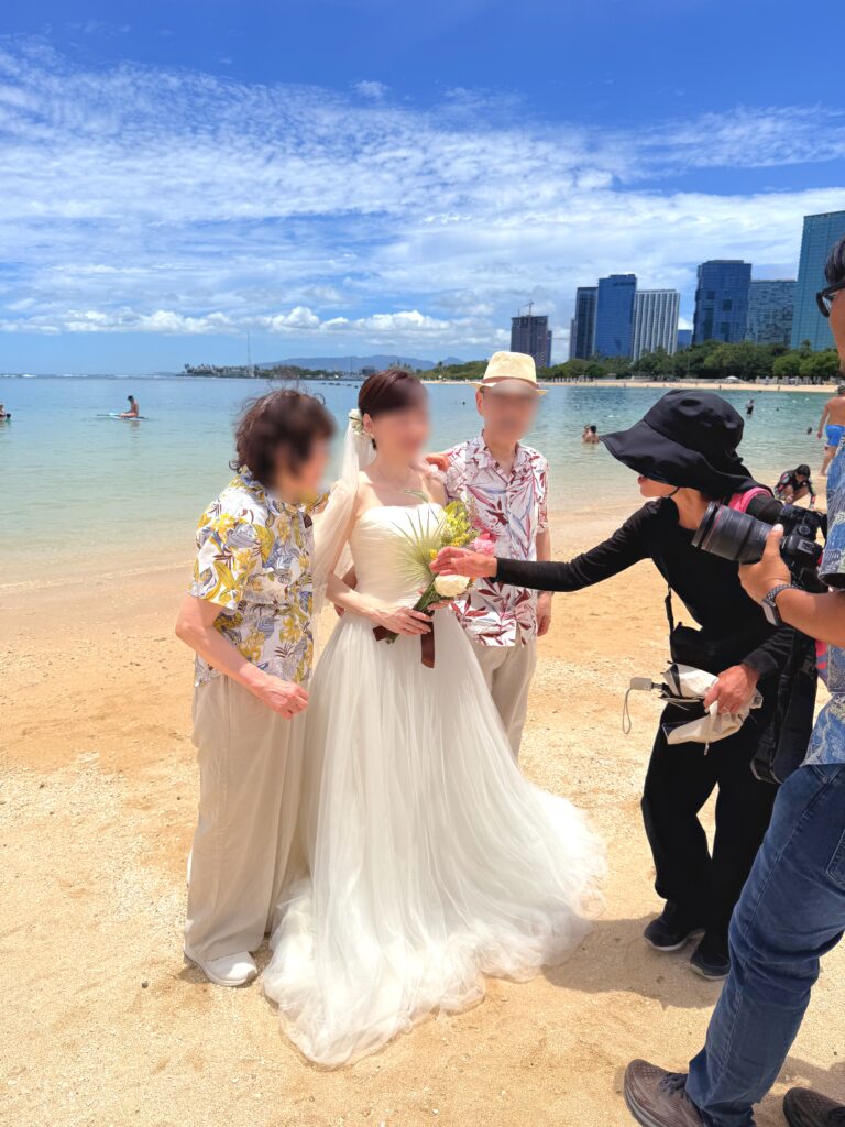 ハワイのビーチでカメラマン・アテンドスタッフとともにご両親と新婦が撮影を行う風景